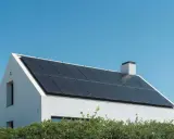 Vitt hus med solpaneler på taket. En strängväxelriktare omvandlar solenergin till användbar el.