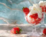 Délicieux dessert fraise melba, glace à la vanille, coulis de fraises et chantilly, garni d'une fraise fraîche.