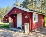 Röda stugor med vita knutar vid Gränna camping. En vit dörr och ett fönster syns på stuga nummer 1.