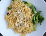 Pyszne cacio e pepe z tartym serem i świeżą sałatką na białym talerzu.