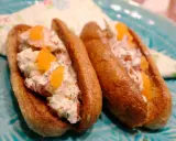 Två lyxiga lobster rolls med krämig fyllning, krispig gurka och orange rom på ett turkost fat.