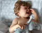 Kleines Kind weint im Schlaf, hält seinen Kuschelhasen fest. Tränen laufen über die Wangen, ein trauriger Moment.