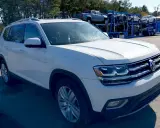 Biały VW Atlas stoi na parkingu, w tle widać lawetę z innymi samochodami.