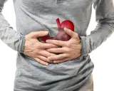 Uomo con mani sullo stomaco, dove un'immagine rossa evidenzia un possibile tumore allo stomaco.