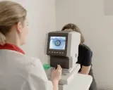 Lekarz od oczu bada wzrok pacjentki za pomocą nowoczesnego urządzenia. Na ekranie widoczny jest obraz oka.