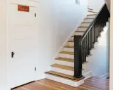 Escalier avec rampe noire et marches en bois clair. La question de peindre une cage d'escalier quelle couleur est ouverte.