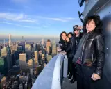 Les membres du groupe KISS posent sur un gratte-ciel new-yorkais, offrant une vue imprenable sur la ville.