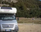 Camper parcheggiato in un'area panoramica della Calabria, con boschi e montagne sullo sfondo. Un'avventura in camper indimenticabile.