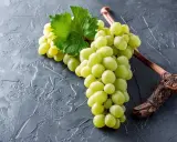 Grüne Trauben, die an einem Ast hängen, sind ein Beispiel für Chardonnay. Diese Rebsorte ist bekannt für ihre vielseitigen Weine.
