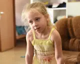 Zmartwiona dziewczynka w żółtej sukience. Co zrobić, gdy dziecko wstrzymuje mocz? Porady dla rodziców.