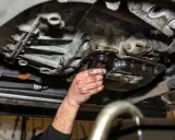 Ręka mechanika sprawdza wyciek z suchej miski olejowej.