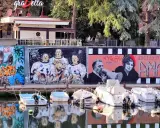 Graffiti colorati sul muro del borgo San Giuliano: astronauti con Alf, personaggi di Amarcord e cani. Barche ormeggiate sull'acqua riflettono i colori.