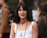 Frau mit langen Haaren und Curtain Bangs, trägt weiße Tanktop und Chanel-Schmuck.