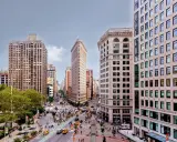 Vista aérea de Nueva York con el icónico edificio Flatiron en el centro. Los planos de la ciudad muestran la intersección de calles y la arquitectura circundante.