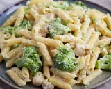 Penne z kurczakiem i brokułami w kremowym sosie, posypane parmezanem. Pyszny makaron z brokułami na talerzu.