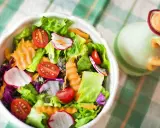 Unas frescas ensaladas de verano con lechuga, tomate, rábano y zanahoria rallada, listas para disfrutar.