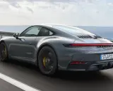 Grauer Porsche 911 Hybrid rast auf einer Küstenstraße.