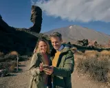 Pareja sonriente en un paisaje volcánico, quizás planeando su visita al museo de la naturaleza y el hombre.