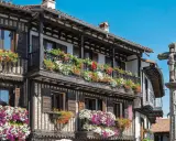 Casas de madera y piedra adornadas con flores en la Sierra de Francia. Un crucero de piedra se alza en la plaza.
