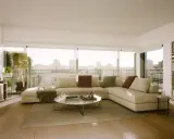 Un salón moderno y luminoso con sofá seccional, mesa de centro, estantería y vistas a la ciudad. ¡Inspírate para diseña tu salón!