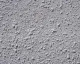 Textura gris de pared con relieve irregular, típica del **el gotelé**, que crea un efecto rugoso y con pequeñas protuberancias.