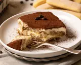 Ein Stück Tiramisu, perfekt für ein Tiramisu Rezept, mit Löffelbiskuit, Creme und Kakaopulver bestäubt.