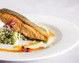 Wykwintna fotografia jedzenia: soczysty łosoś z chrupiącą skórką, podany na kaszy z ziołami i kremowym puree.