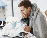 Uomo malato, avvolto in una coperta, prende una pillola. Spera che l'aspergillus si guarisca presto.