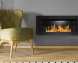 Sillón verde junto a chimenea moderna encendida. Un ejemplo de como encender la chimenea para crear un ambiente acogedor.