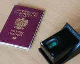 Polski paszport i czytnik linii papilarnych na drewnianym blacie.