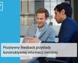 Dwóch mężczyzn w garniturach rozmawia przy biurku. Jeden z nich gestykuluje, omawiając pozytywny feedback dla pracownika, przykłady konstruktywnej informacji zwrotnej.