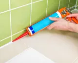 Application de silicone pour maçonnerie sur un joint de carrelage.