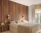 Dormitorio con cabecero de madera natural, creando un ambiente sereno y un cabecero feng shui. Cama confortable con mantas cálidas y luz tenue.