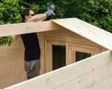 Hombre ensamblando una caseta de jardín con maderas para exterior.