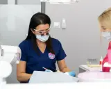 Dentystka w okularach i masce pracuje przy pacjencie. Dyskutują, jak przyspieszyć schodzenie znieczulenia.