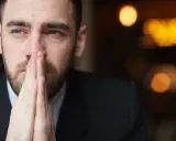 Zamyślony mężczyzna z dłońmi złożonymi do modlitwy. Czy to znak, że trwa żałoba po bracie, ile czasu jeszcze minie, zanim ból ustąpi?