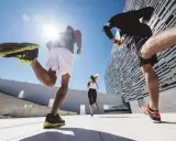 Ludzie uprawiający marszobieg w słoneczny dzień, co to za aktywność? Biegacze w sportowych strojach pokonują dystans na tle nowoczesnej architektury.