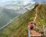 Wanderer erklimmen die "Stairway to Heaven" in Hawaii, eine steile Treppe mit atemberaubendem Blick auf die Stadt und die Natur.