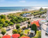 Blick auf Strandpromenade mit Seebrücke, Ostsee und Hotelterrasse mit Pool.