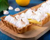 Tarta de limón con abundante merengue suizo tostado, sobre una tabla de madera.