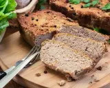 Domowy pasztet, idealny do pieczenia w temperaturze 180°C, pokrojony na desce z widelcem i sałatą.