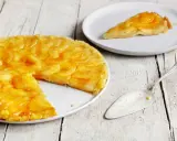 Eine goldbraune Tarte Tatin mit karamellisierten Äpfeln auf einem Teller, daneben ein Stück auf einem weiteren Teller und ein Tortenheber.