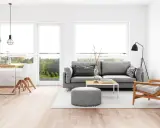 Elegante salón comedor con sofá gris, mesa de centro y sillas blancas. La iluminación es clave para combinar lamparas salon comedor, con colgantes sobre la mesa y una lámpara de pie.