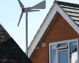 Une petite éolienne maison capte le vent au-dessus des toits.