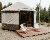 Jurt w otoczeniu lasu, idealne miejsce na agroturystykę pod Poznaniem. Dwa leżaki czekają na tarasie.