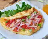 Pyszny omlet bez mąki z szynką, pomidorami i szczypiorkiem, podany z sałatką. Idealny na szybkie śniadanie.