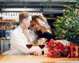 Para świętuje 13 rocznicę ślubu w restauracji, z kieliszkami wina i bukietem czerwonych róż.