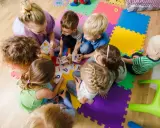 Dzieci i nauczycielka bawią się kartami z literami, ucząc się alfabetu. Ciekawe zajęcia w przedszkolu.
