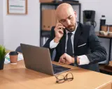 Zmęczony biznesmen sprawdza zegarek, zastanawiając się nad wymiarem czasu pracy.
