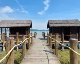 Pontile in legno con due capanne sul lago di Viverone, sotto un cielo azzurro con nuvole bianche.